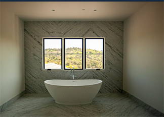 A freestanding bathtub beneath three windows