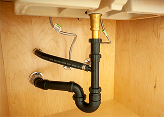 Pipes running underneath a sink inside a cabinet